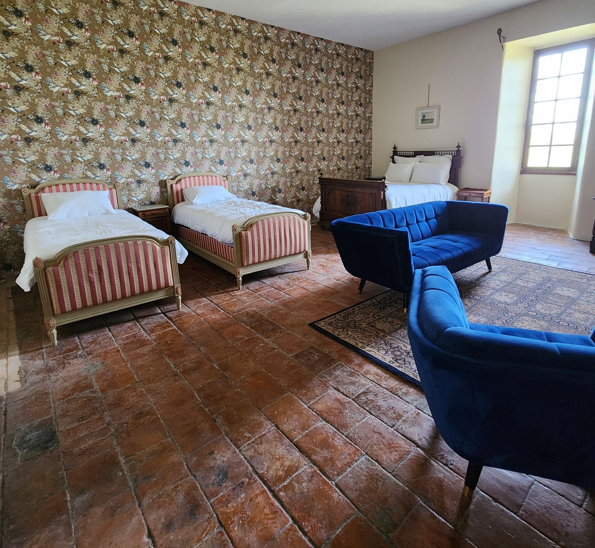 Chambre avec lit en bois orné, papier peint fleuri et lampes de chevet.