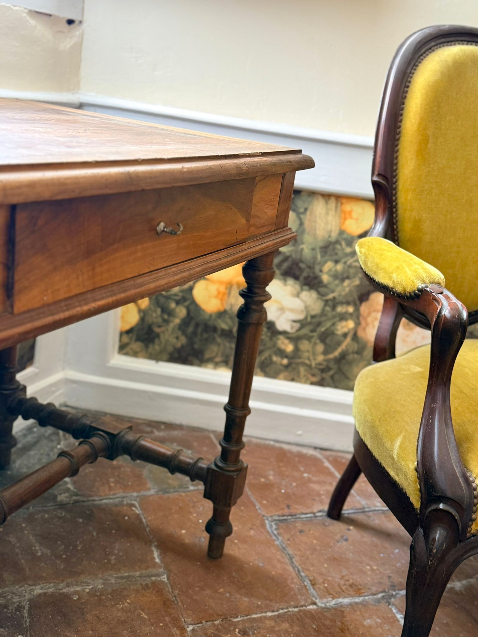 Une table en bois à côté d'un fauteuil recouvert de velours jaune.