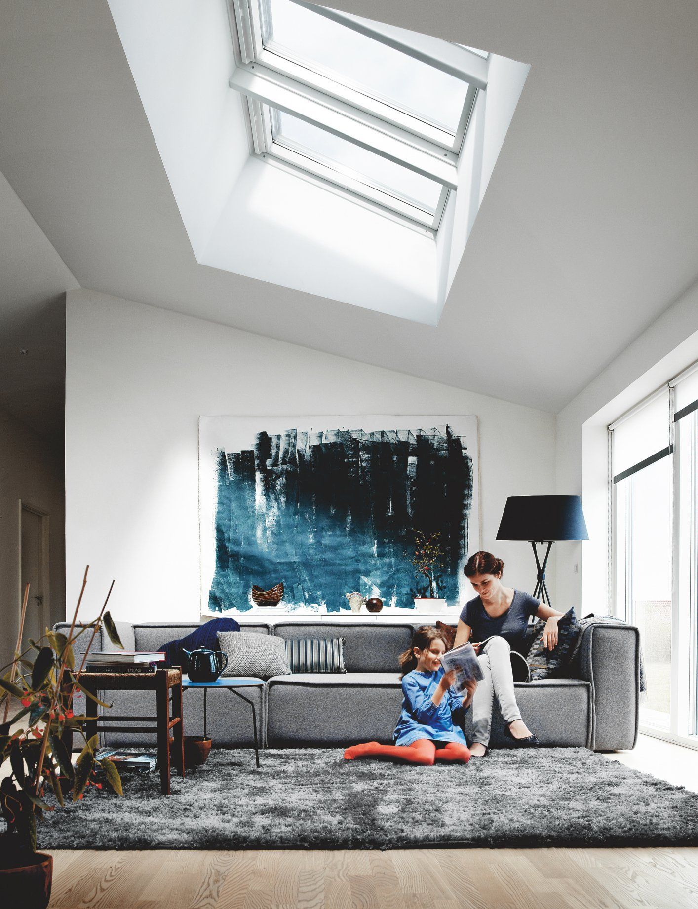 Living room with a skylight, a sofa, and two people looking at something.