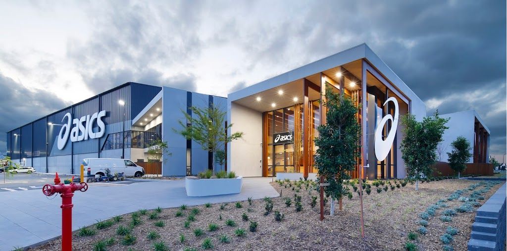 ASICS store exterior with large logo, modern architecture, cloudy sky.