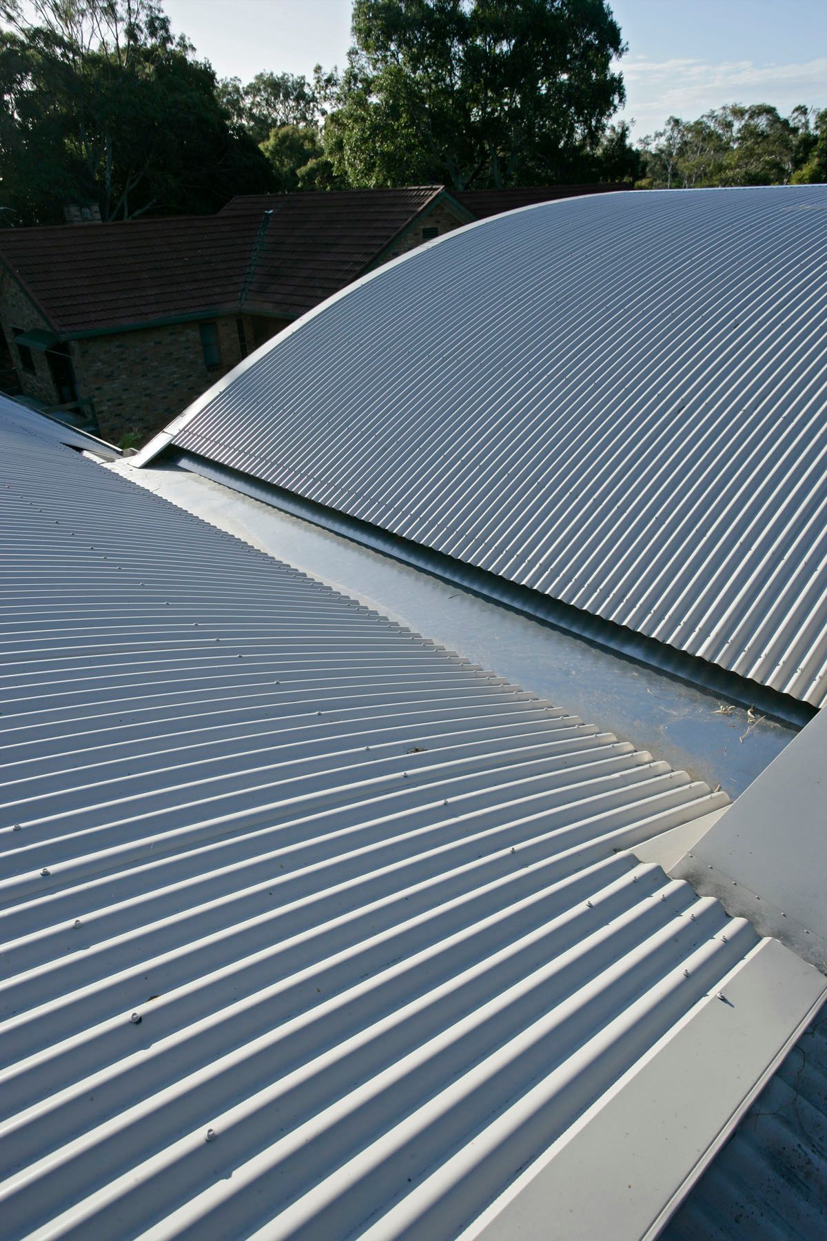 Corrugated metal roof with curved design; shadows cast by the sun.