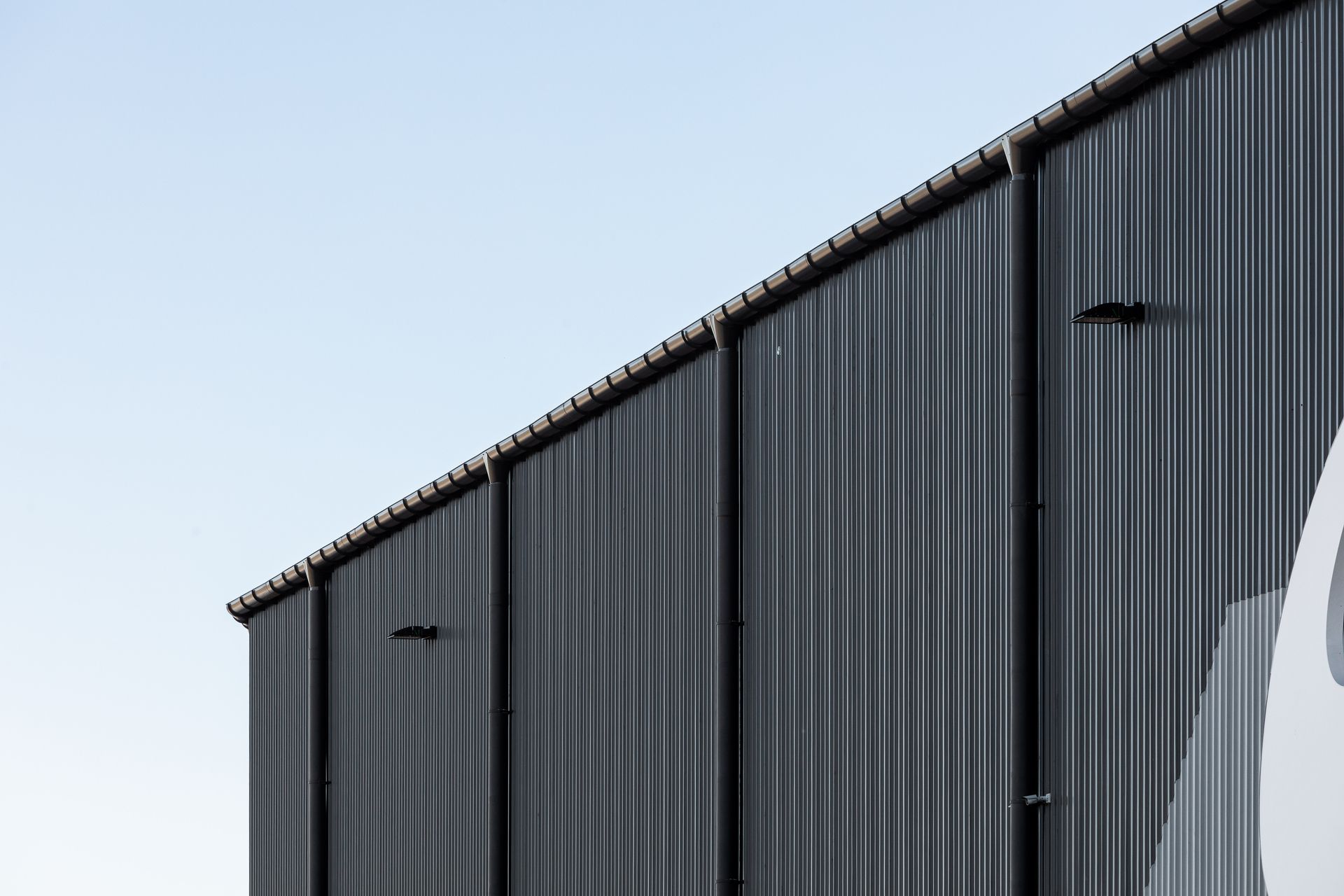 Dark corrugated metal building against a blue sky.