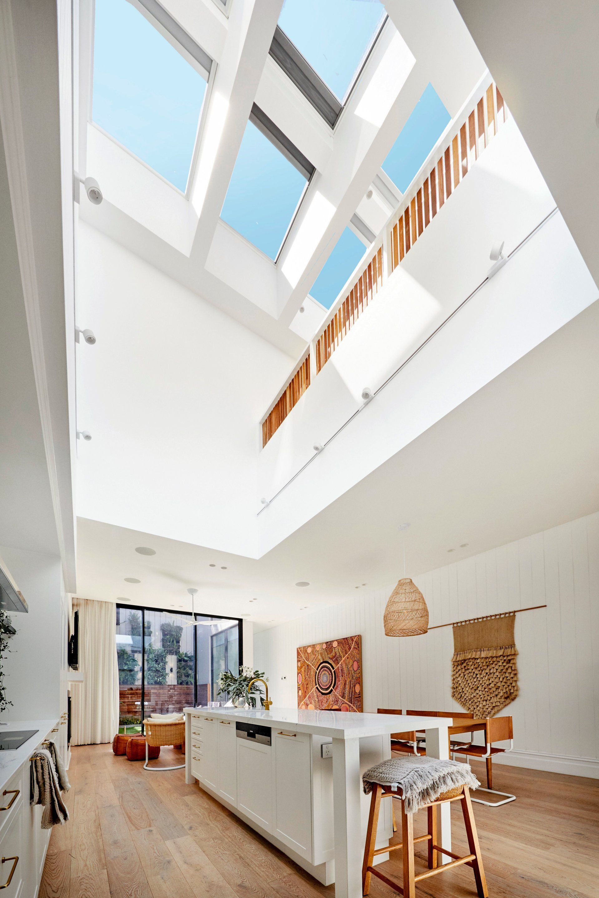 Modern kitchen with skylights, light wood floors, white island, and decorative wall art.