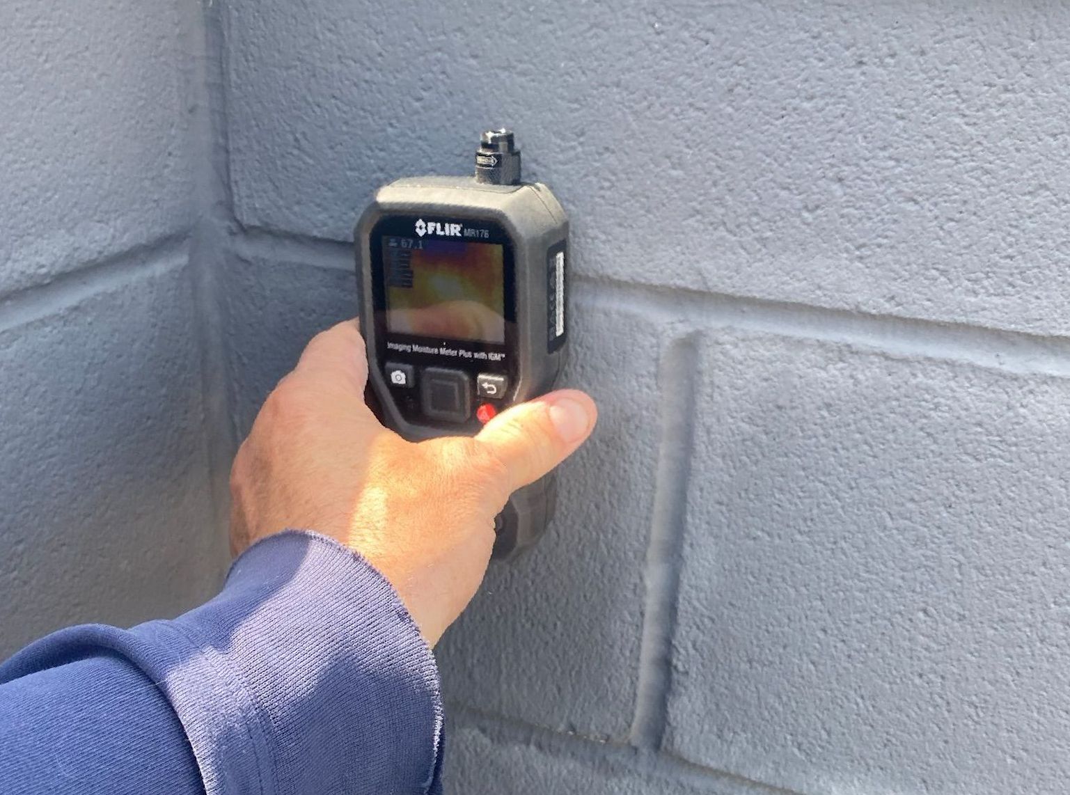 Moisture meter on wet cement block wall showing 85 percent moisture - average normal moisture content is 30 percent or less.
