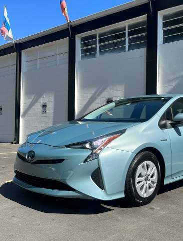 A Toyota Prius is parked in front of a building - In Stock Auto Outlet & Collision