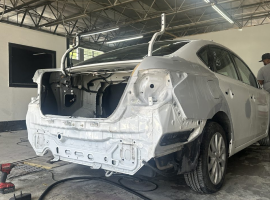 A white car is being repaired in a garage | In Stock Auto Outlet and Collision