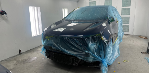 A car is wrapped in plastic in a paint booth | In Stock Auto Outlet and Collision