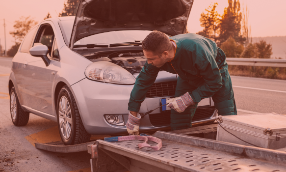 A man is looking under the hood of a broken-down car | In Stock Auto Outlet and Collision