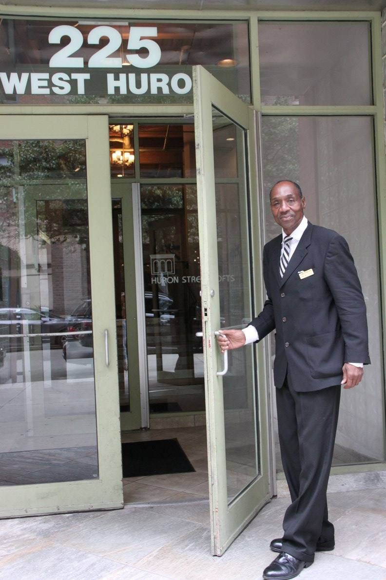 A man in a suit is standing in front of a building that says 225 west huro