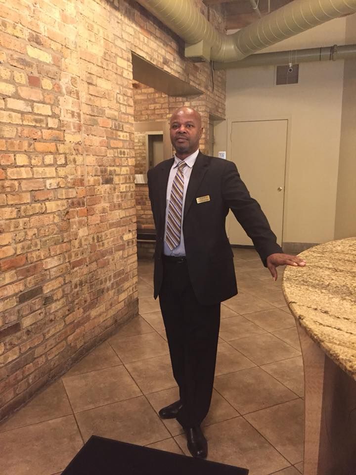 A man in a suit and tie is standing in front of a brick wall.