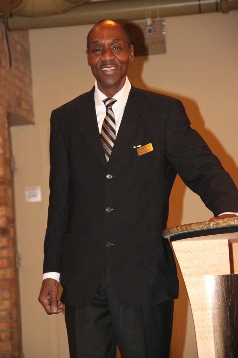 A man in a suit and tie stands in front of a podium