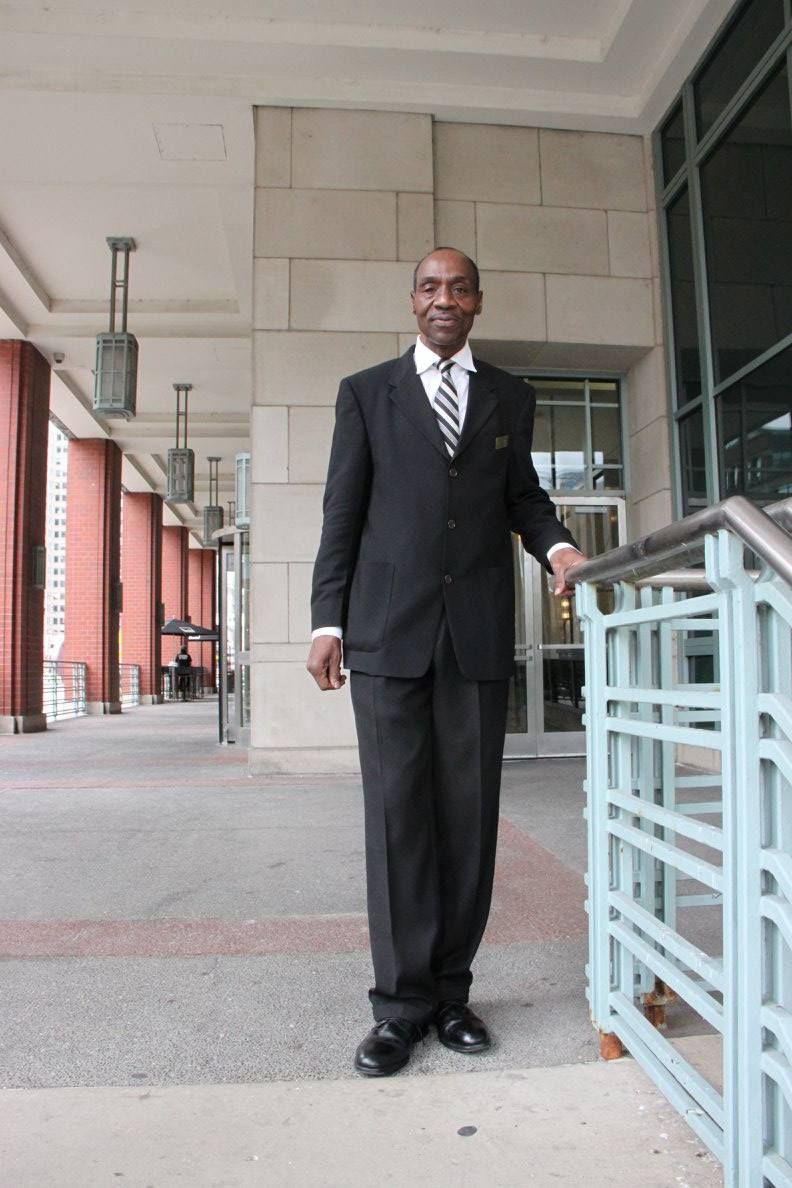 A man in a suit and tie stands in front of a building