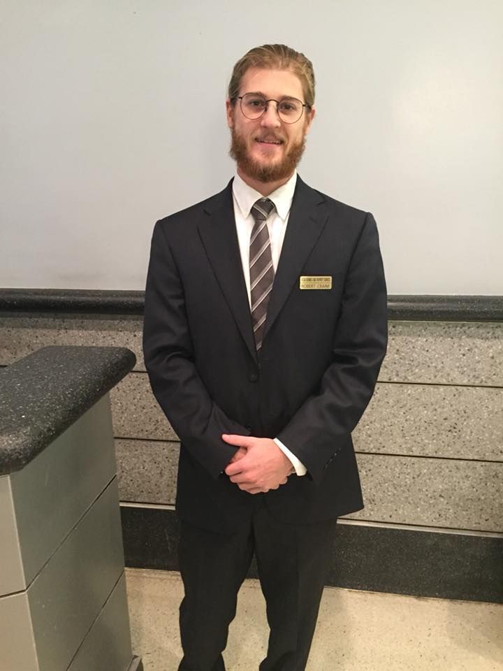 A man in a suit and tie is standing in front of a counter.