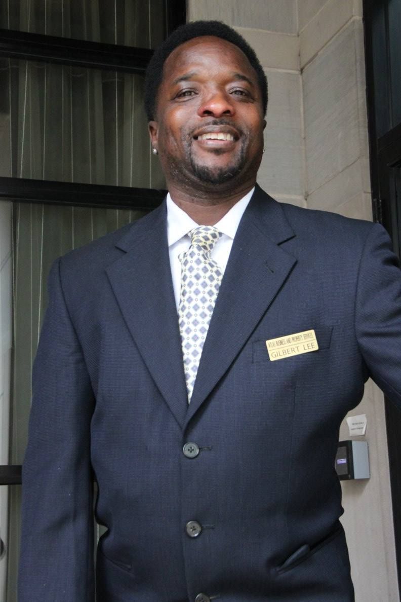 A man in a suit and tie has a name tag on his pocket