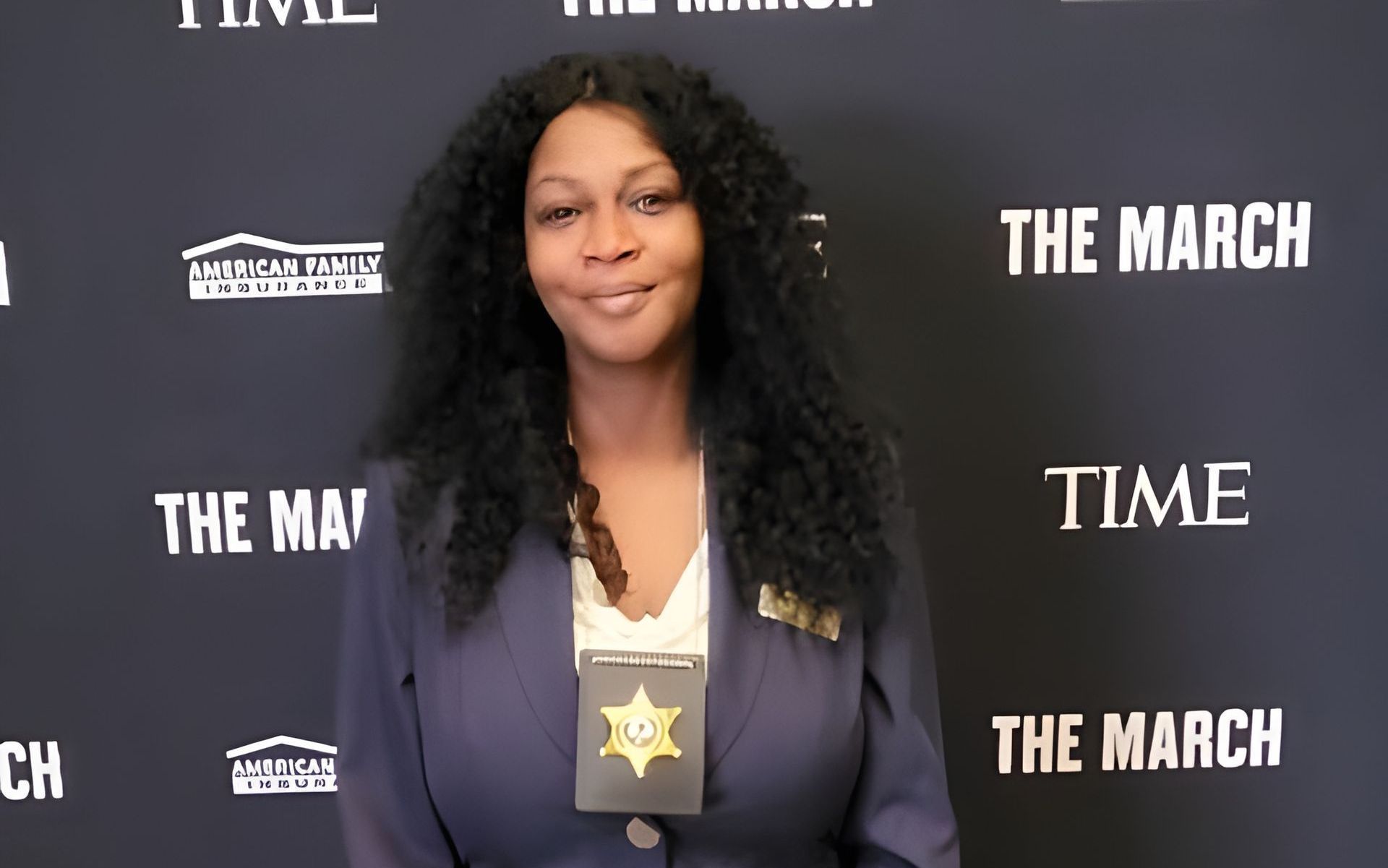 A woman stands in front of a wall that says the march