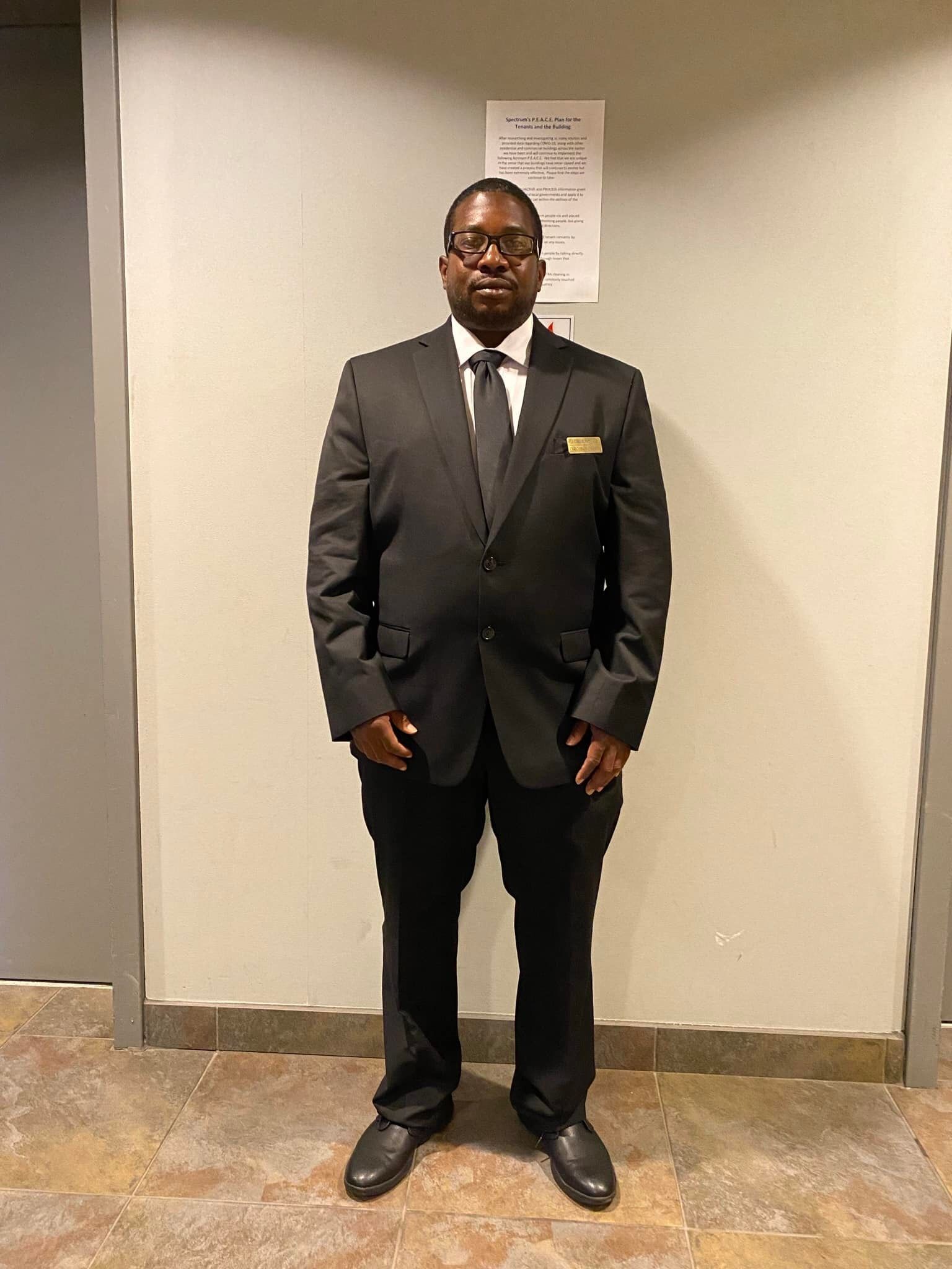 A man in a suit and tie is standing in front of a wall.