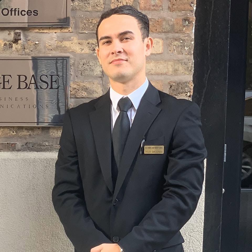A man in a suit and tie is standing in front of a plant