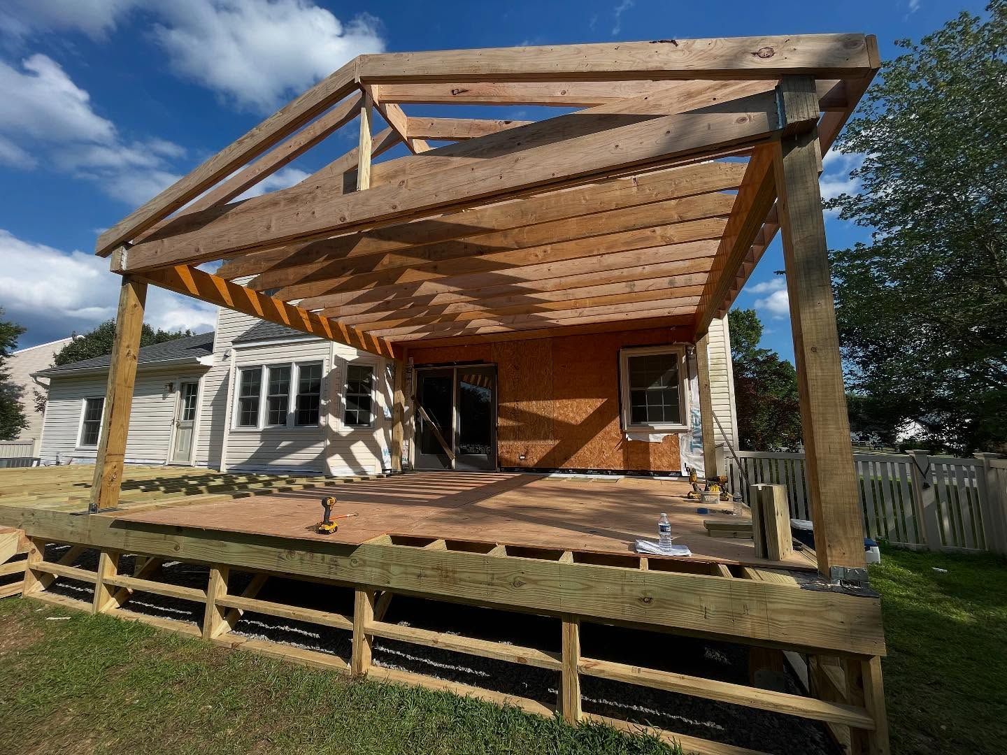 Woman in straw hat smiles, holding wine glass near a lake.
