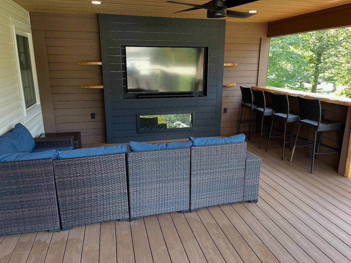 Woman in straw hat smiles, holding wine glass near a lake.