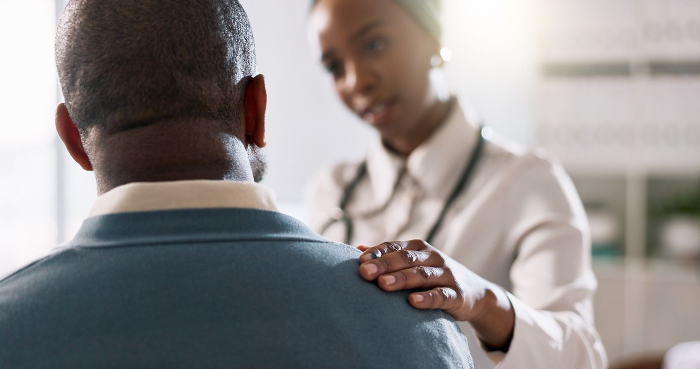 Doctor comforts patient, hand on shoulder. Medical setting, warm lighting.