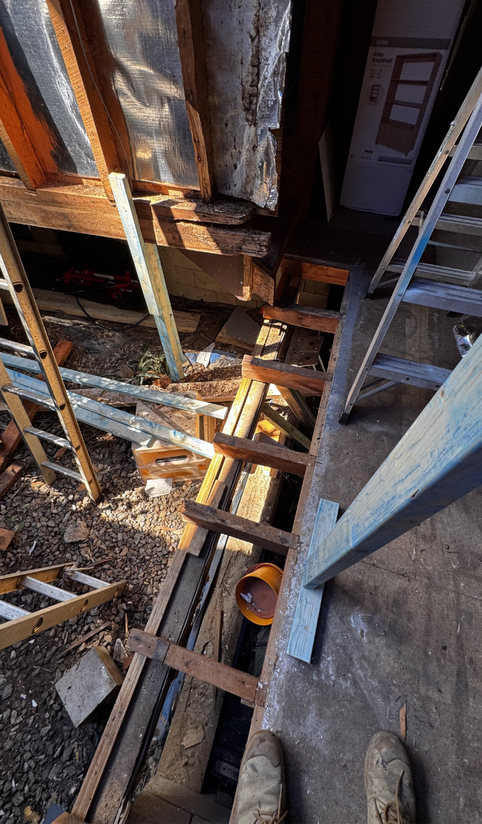 Rusty metal beams and wooden planks in a narrow construction or demolition space, viewed from above