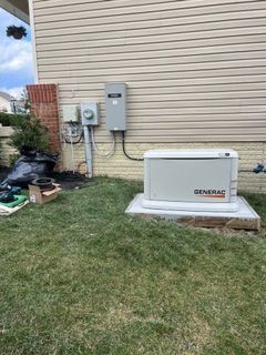 A Generac home backup generator on gravel next to a house, with vapor emitting.