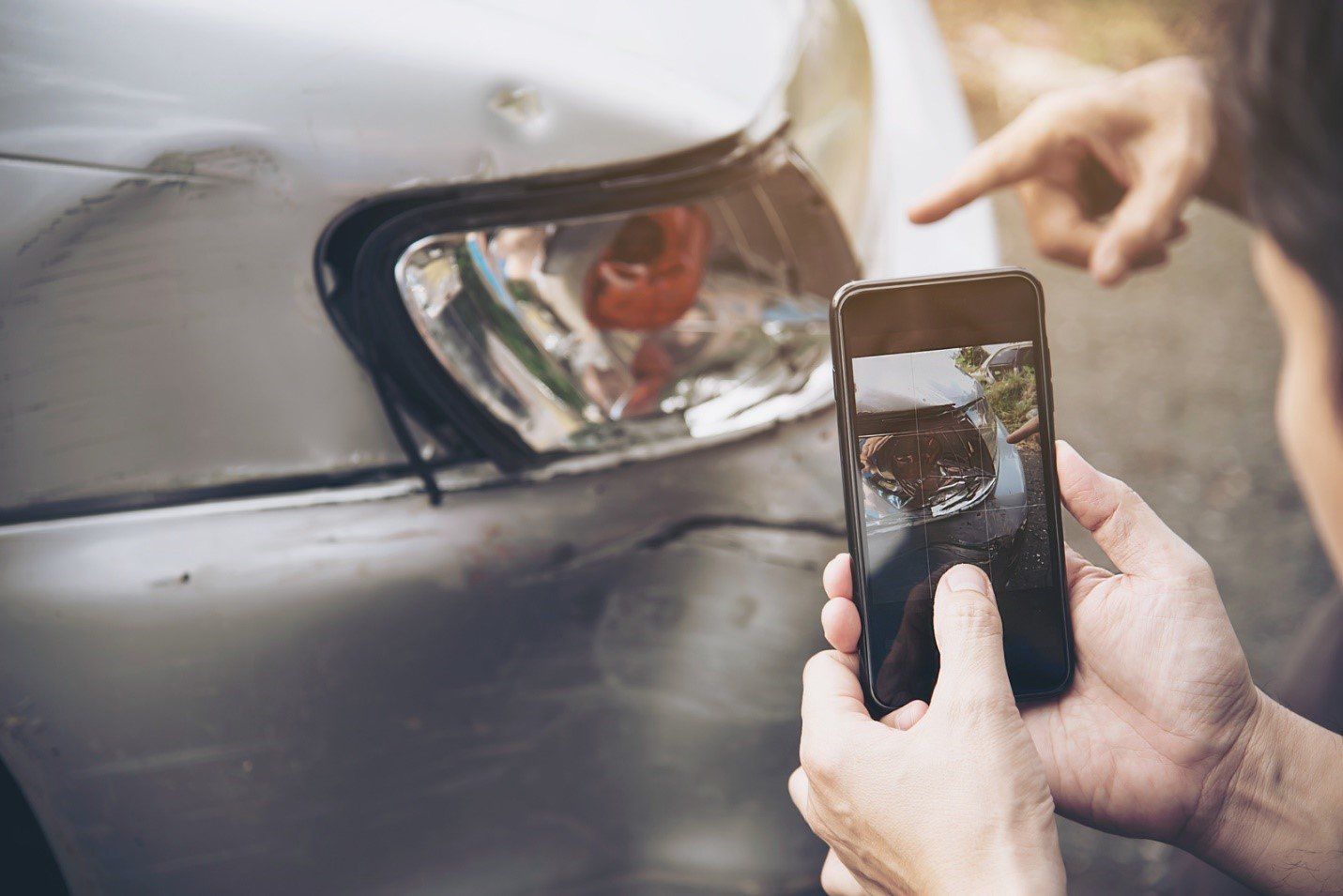 A person taking a video of a damaged car after an accident.