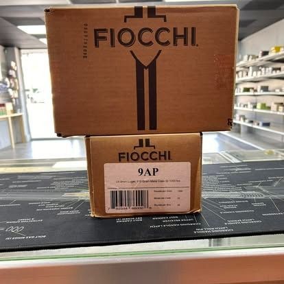 Boxes of Fiocchi ammunition on a counter in a store. One box is larger, brown, and on top.