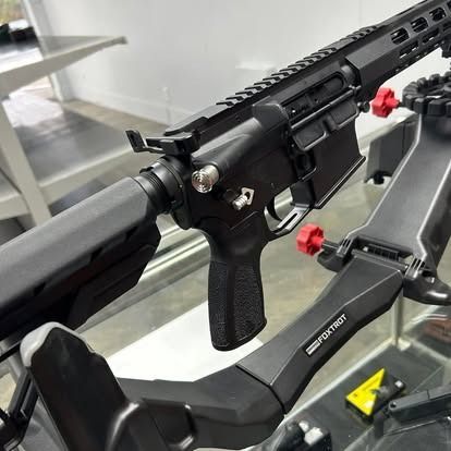 Black AR-15 rifle on a black gun stand, displayed indoors.