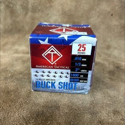 Box of American Tactical 12-pellet buckshot ammunition, red, white, and blue, with 25 rounds, in a brown setting.