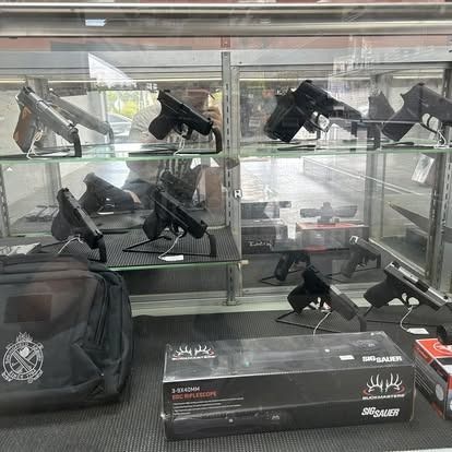 Gun store display case with various handguns and a case.