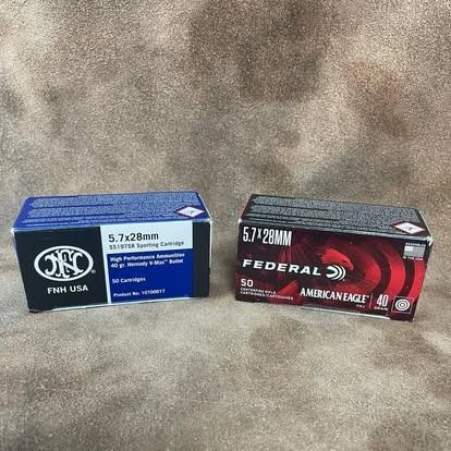 Two boxes of 5.7x28mm ammunition, FN and Federal American Eagle, on a brown surface.