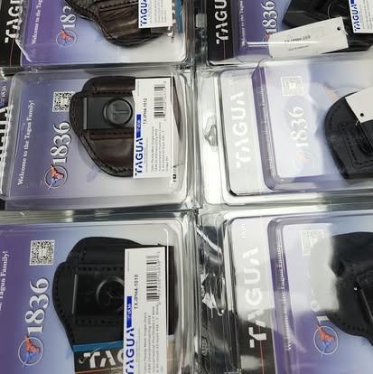 Packages of Tagua 1836 gun holsters in various colors, displayed on a shelf.