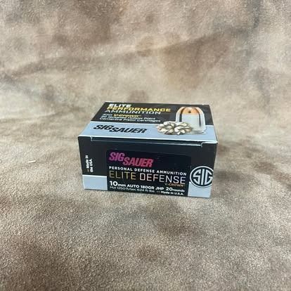 Box of SIG Sauer Elite Defense ammunition on a textured brown surface.