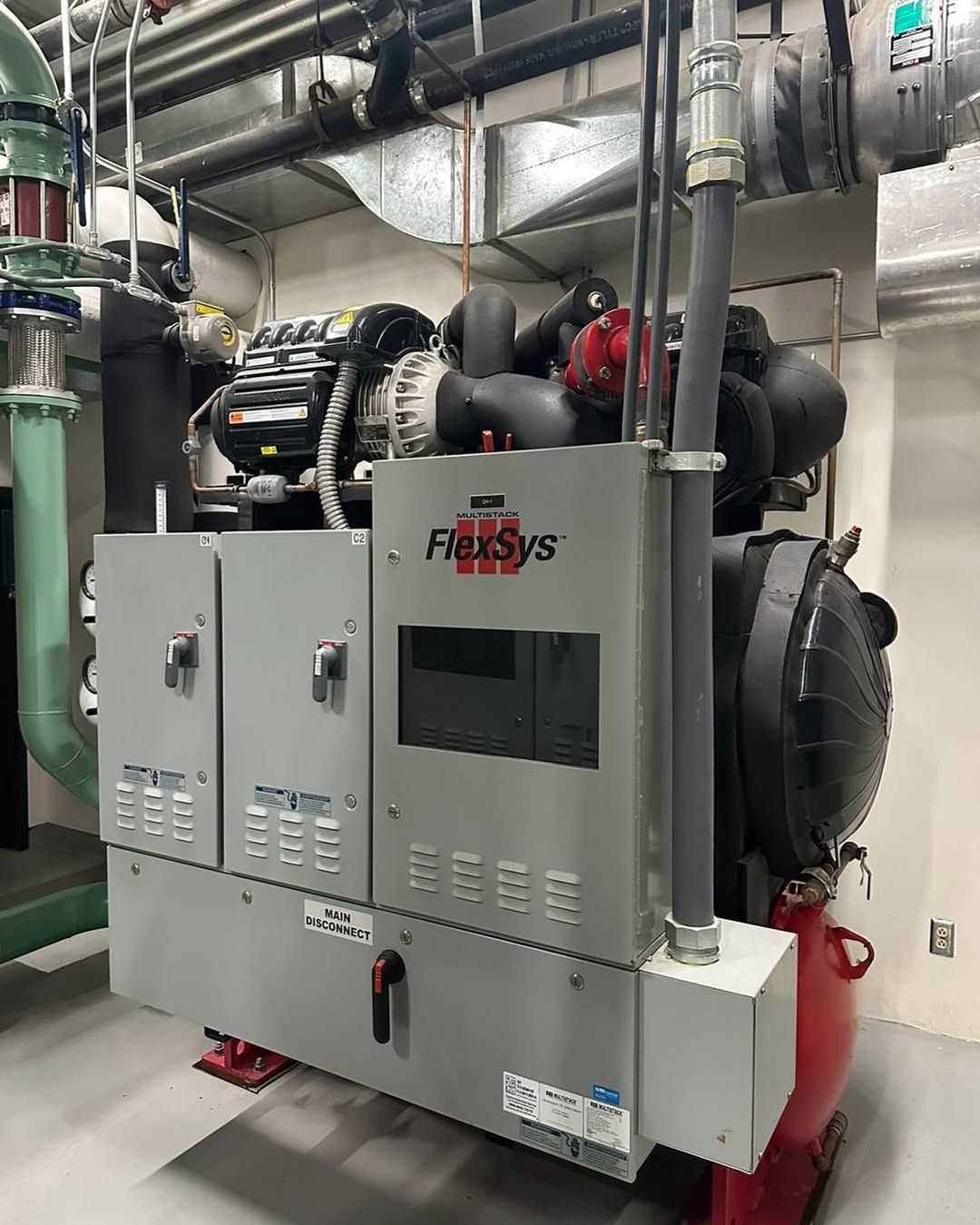 A large machine is sitting in a room with a lot of pipes.