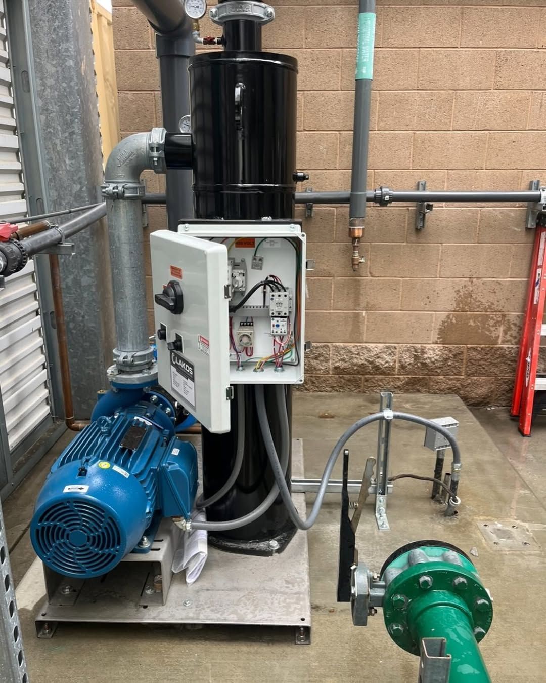 A blue motor is sitting next to a green pipe.