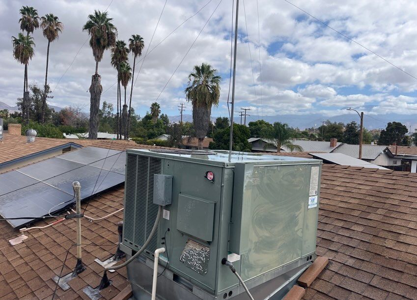 A rooftop air conditioner is sitting on top of a roof next to solar panels.