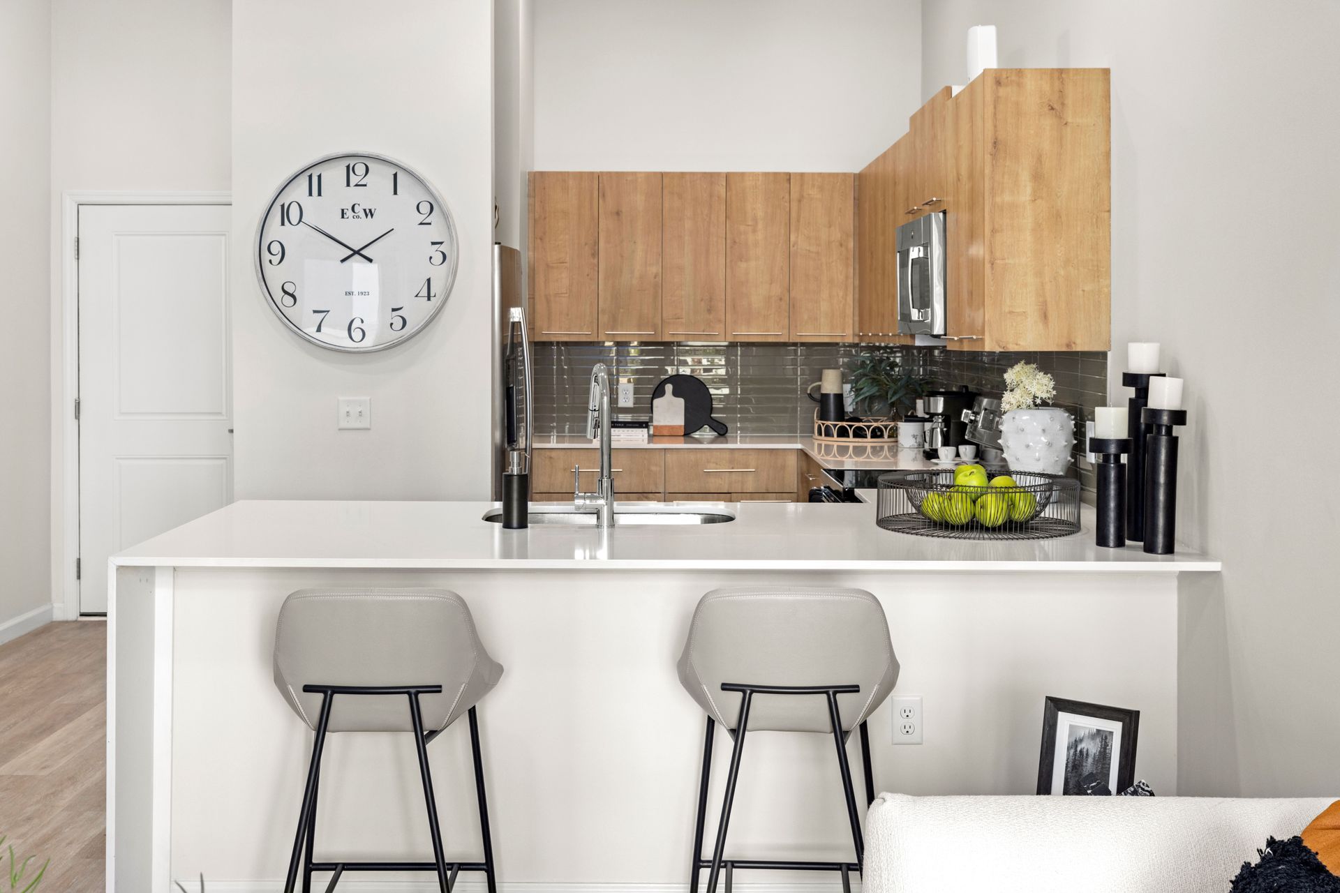 A kitchen with a clock on the wall above the counter.