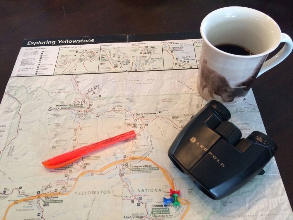 Planning a Yellowstone park trip  using a map along with a coffee cup and binoculars