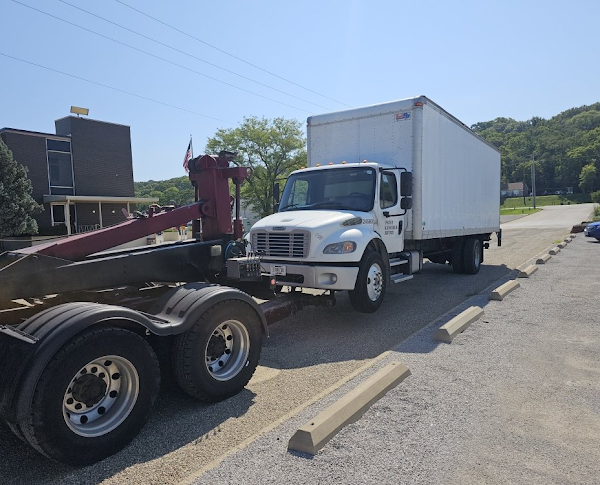 A white truck is being towed by a red tow truck