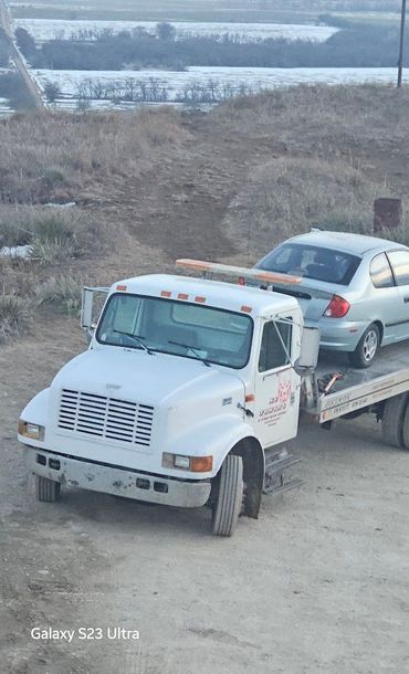 A tow truck is carrying a car on the back of it.