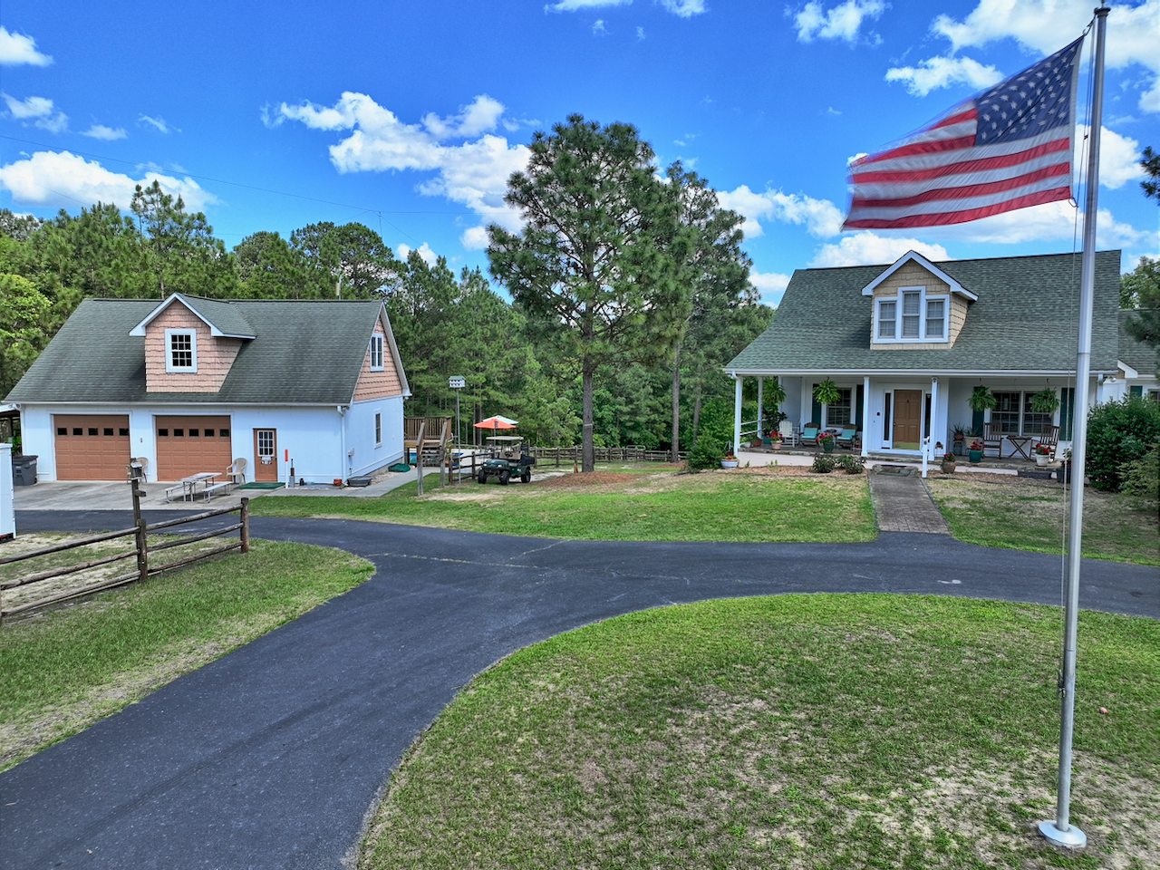 A two story house with workshop, pool and horse barn behind a waving American flag