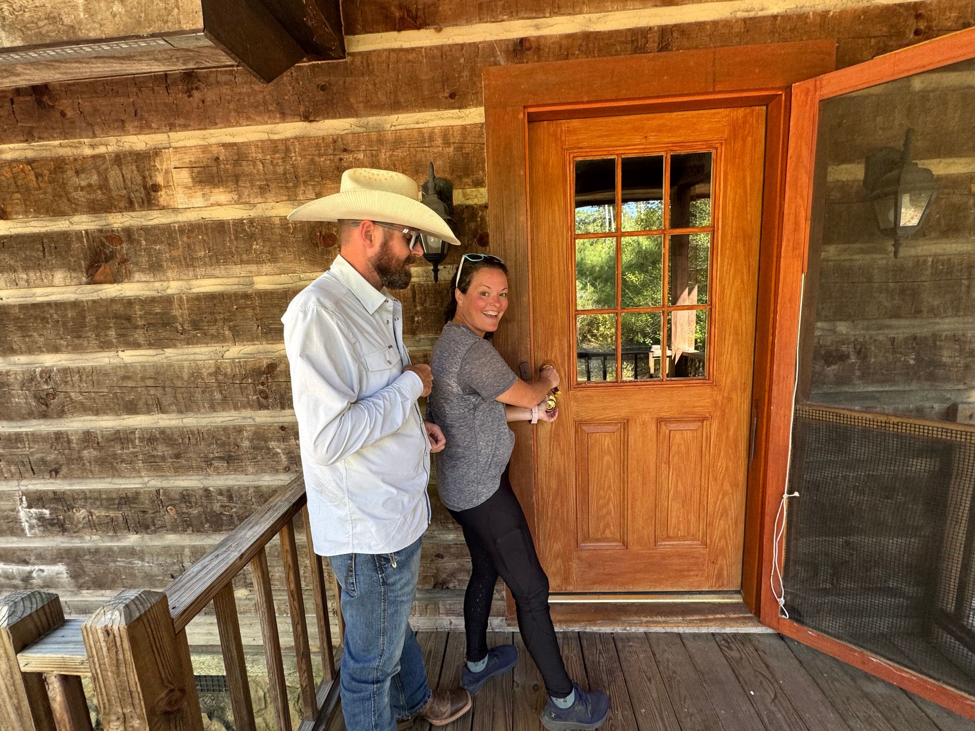 A couple opening the front door of their log cabin home