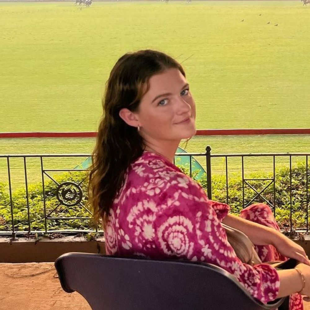 A woman is sitting in a chair with a field in the background