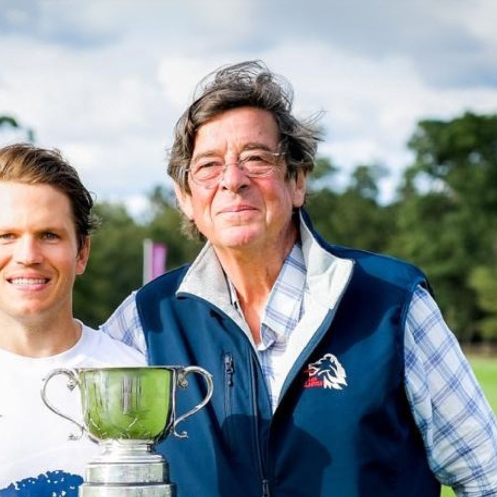 Two men standing next to each other holding a trophy