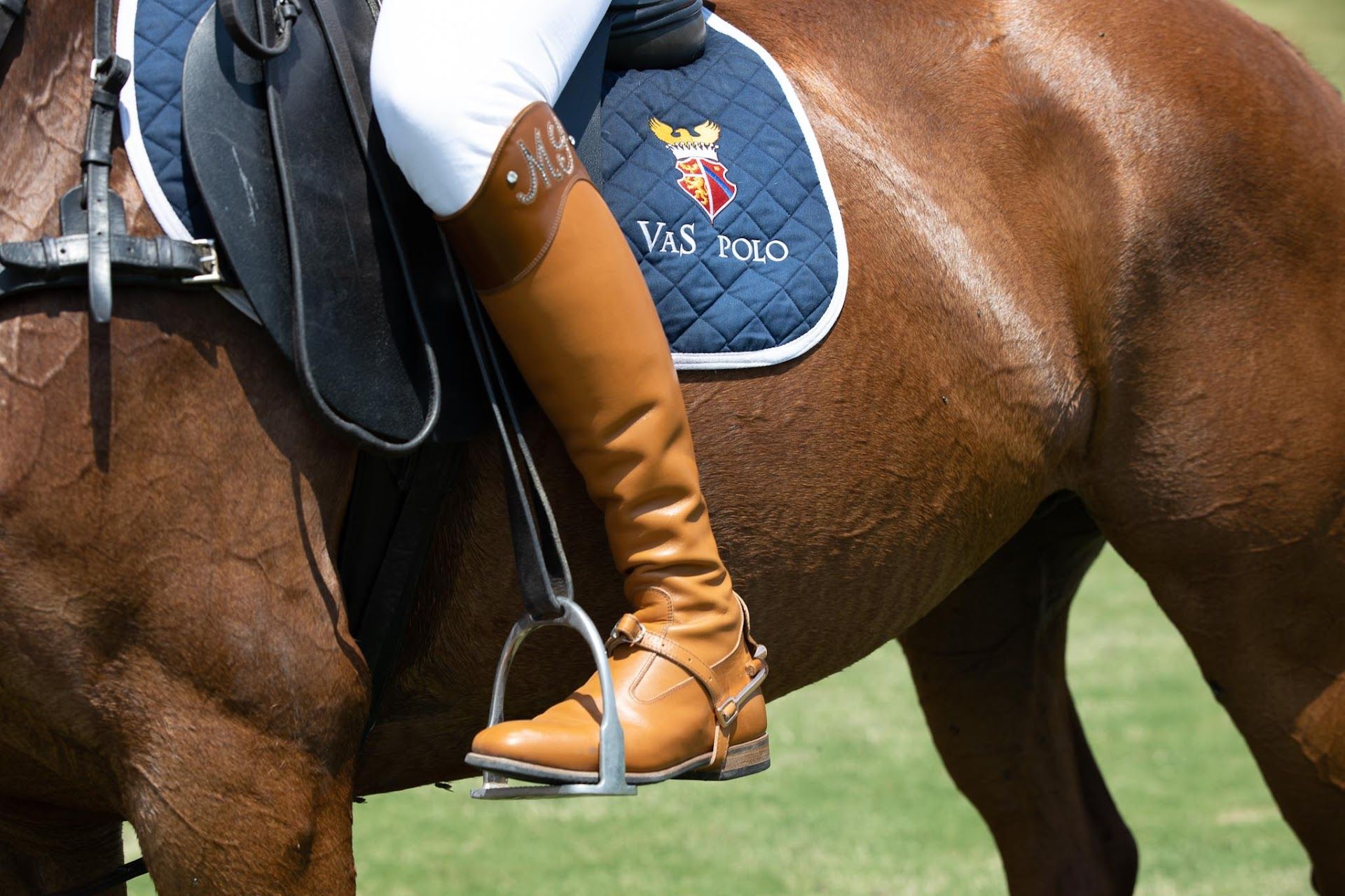 A person riding a horse with a saddle that says vas polo
