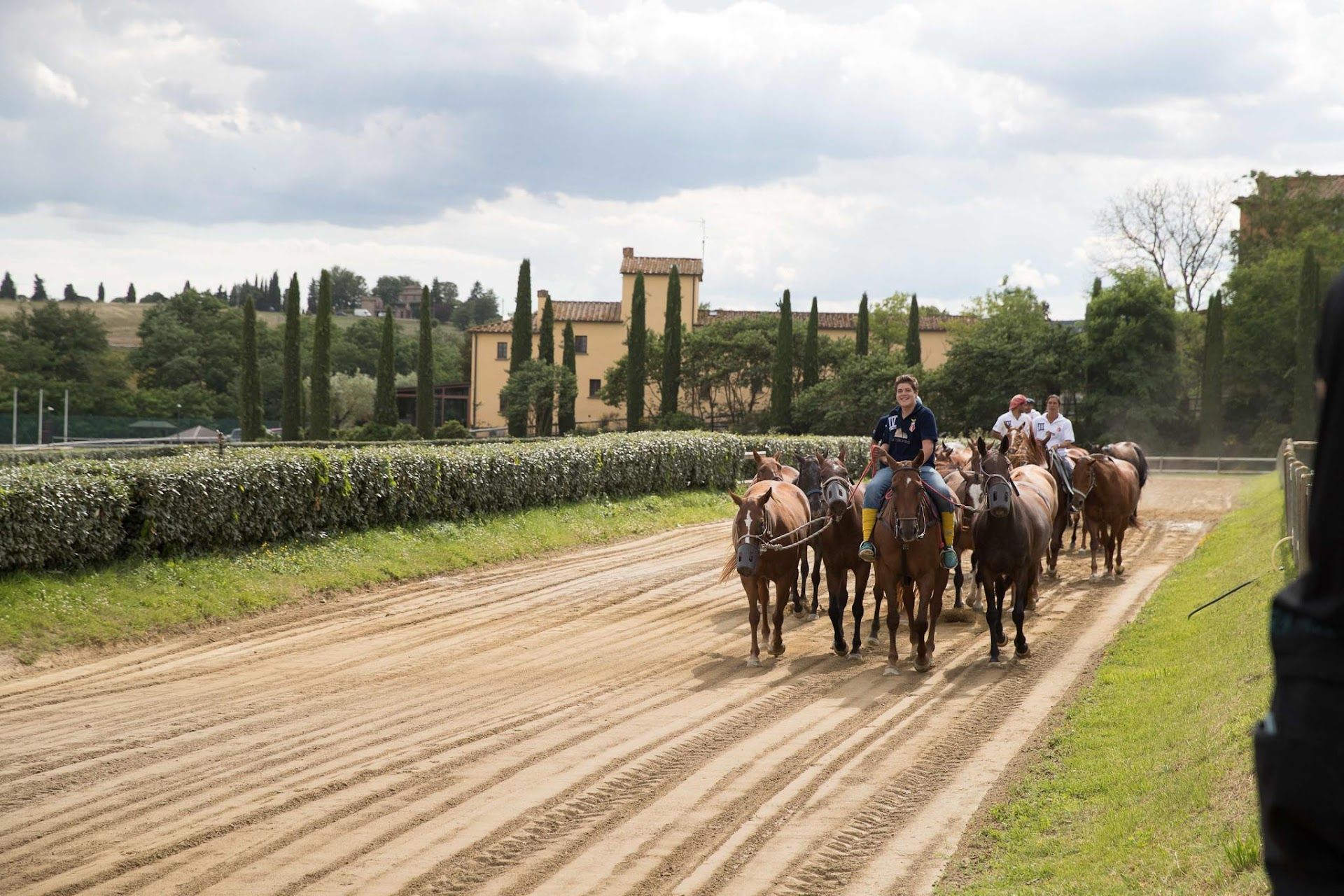 A group of people are riding horses down a dirt road.