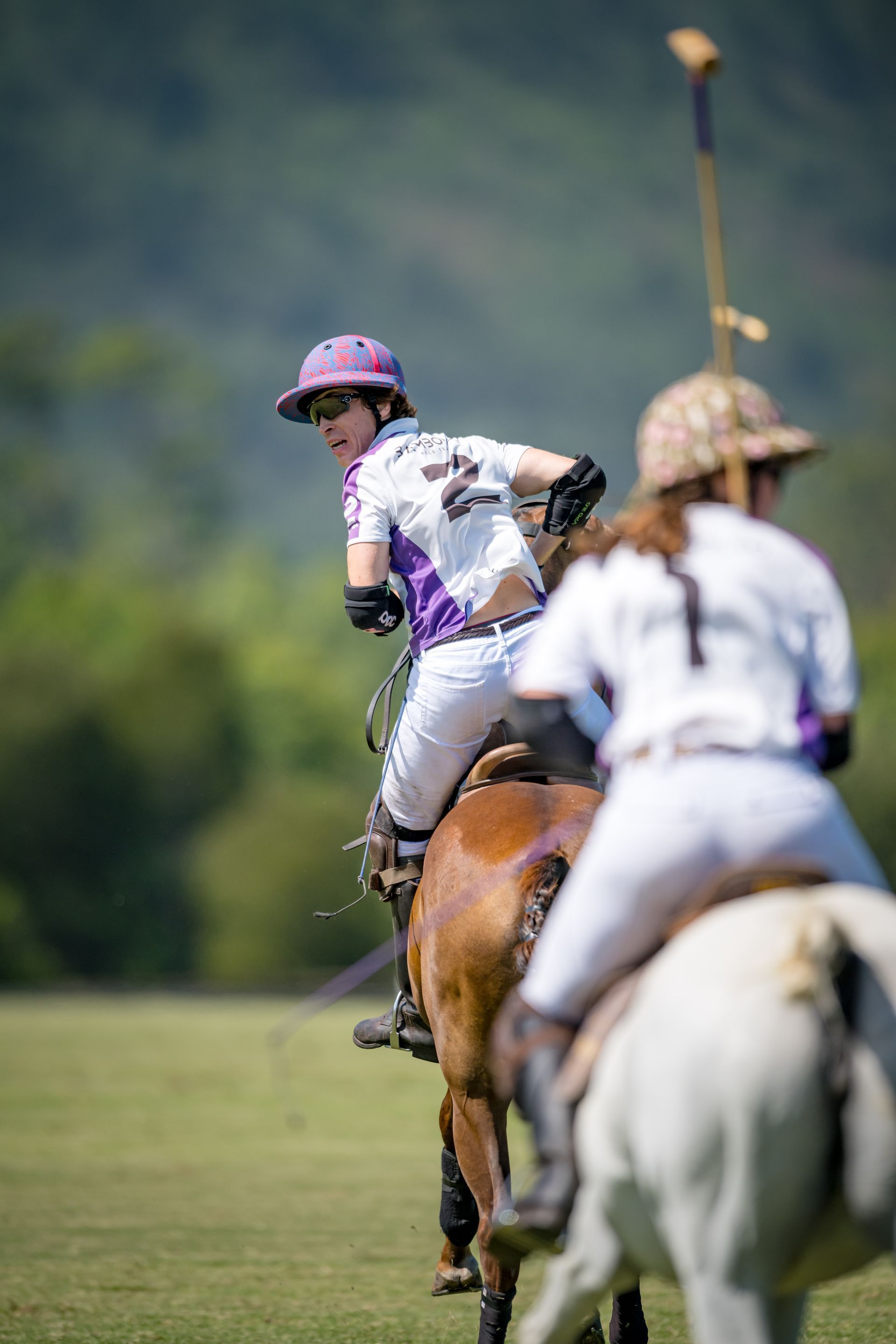 A group of people riding horses on a field playing polo.