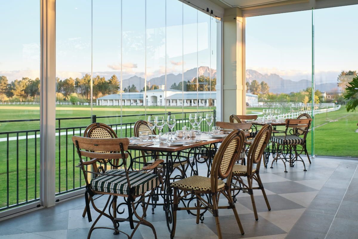 A patio with tables and chairs and a view of a golf course.