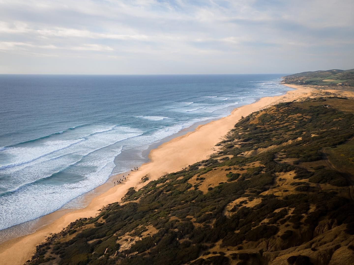 An aerial view of a long sandy beach next to the ocean.